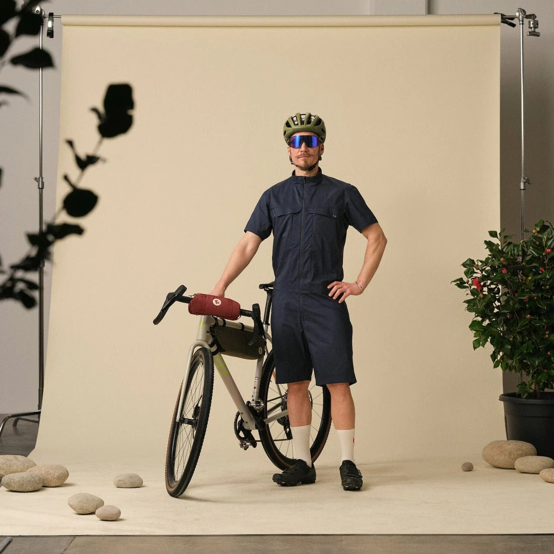Man in cycling gear with a bicycle against a neutral backdrop